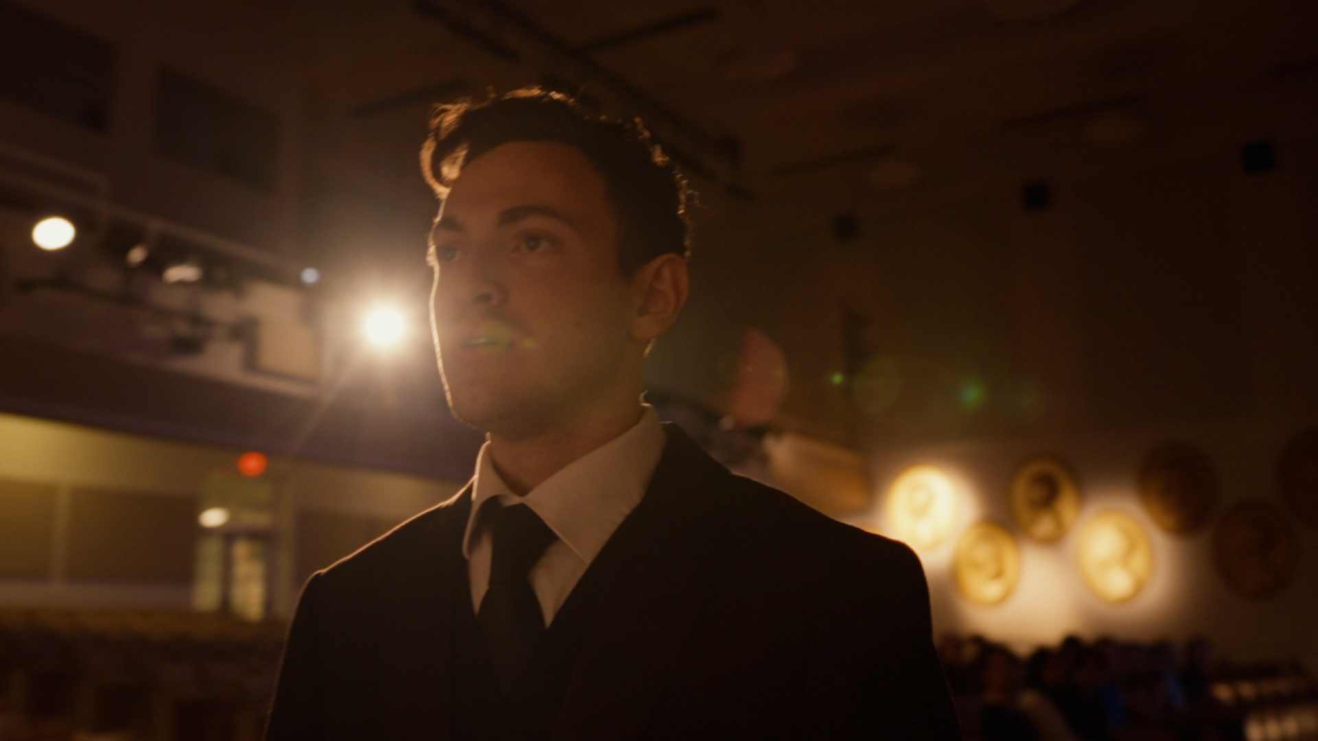 A man in a suit and tie fixing his eyes on a subject out of frame.