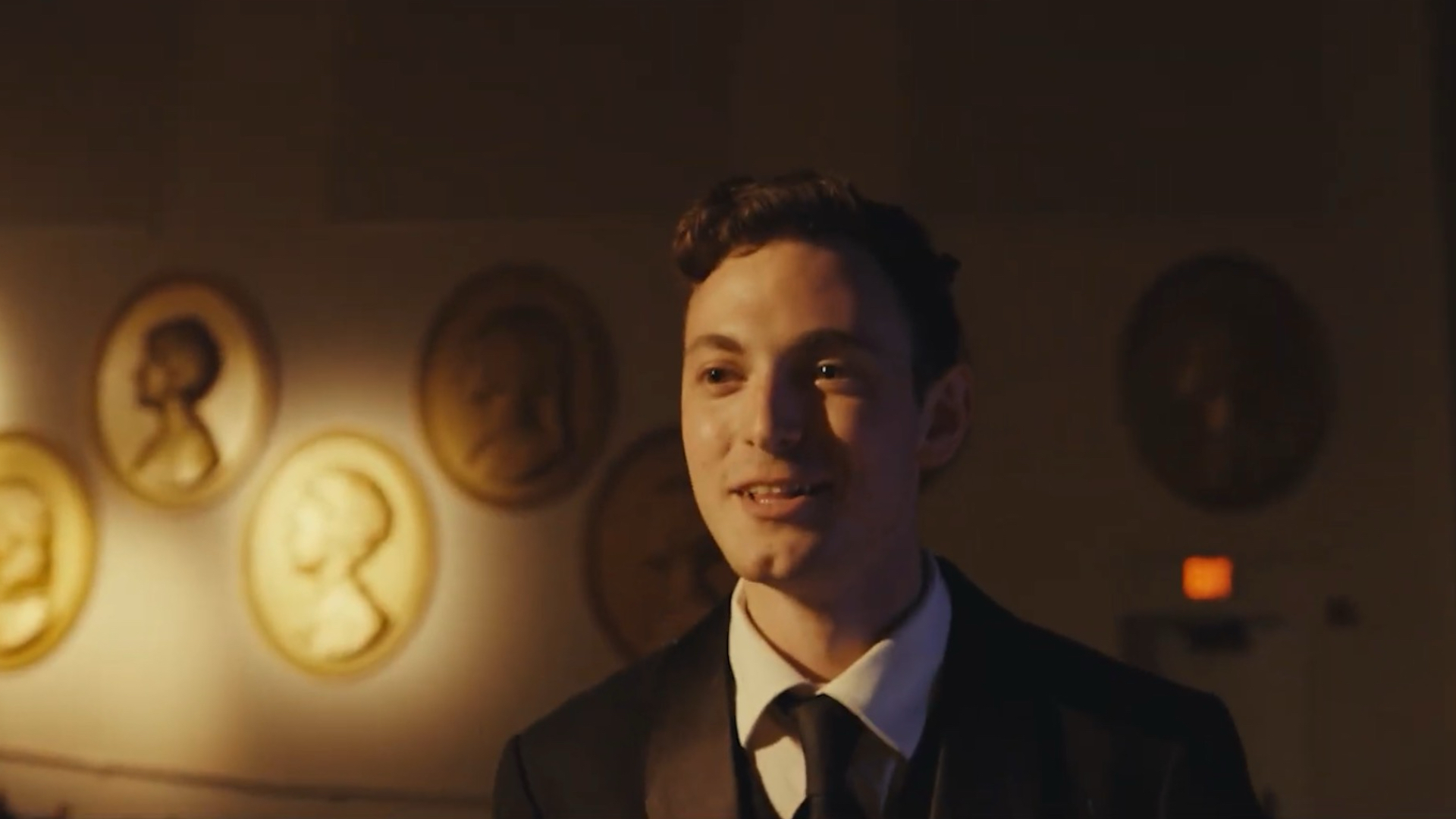 Man in a suit and tie smiling at something in the distance
