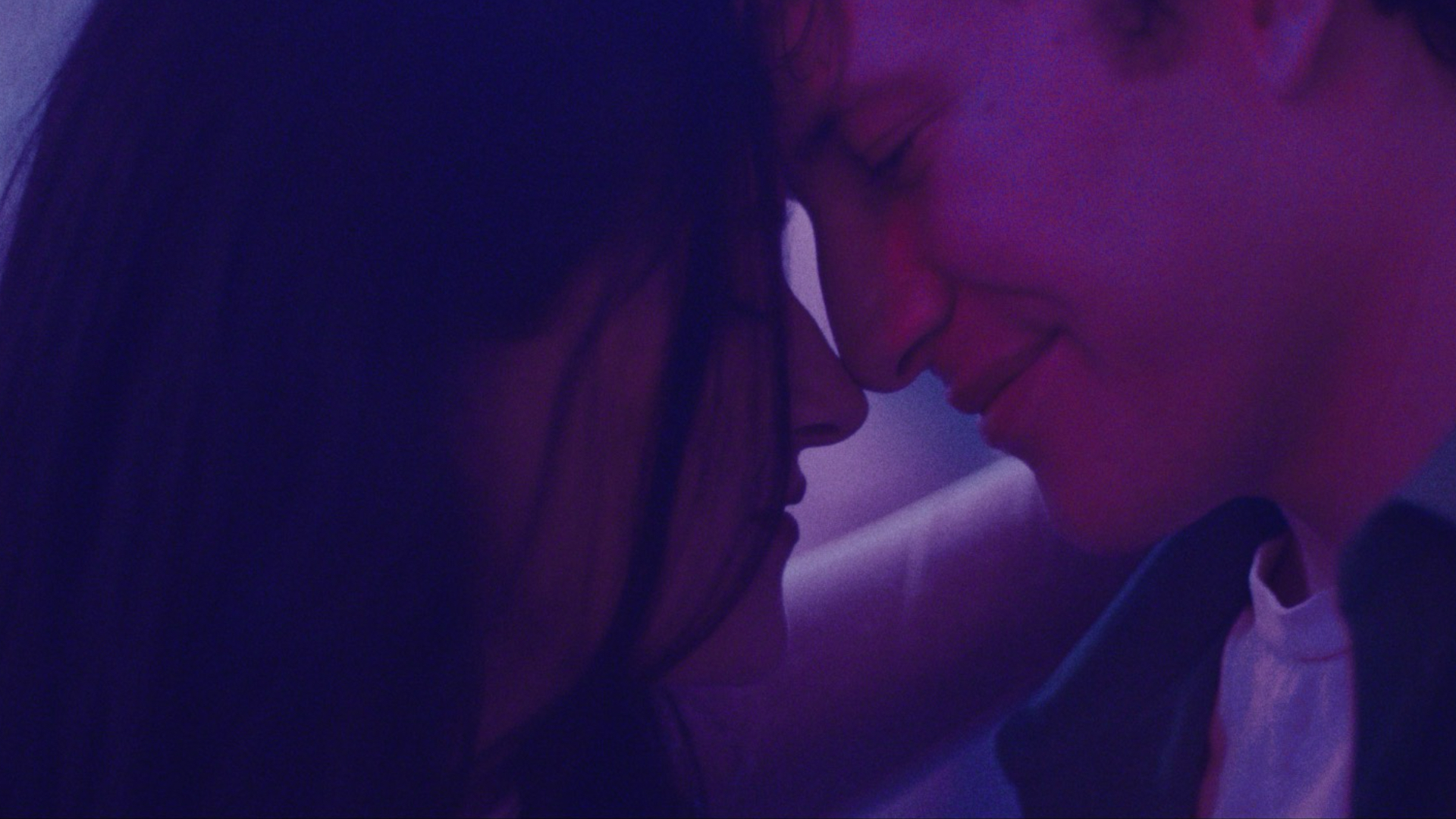 Two people, seemingly lovers, holding onto each other as they dance